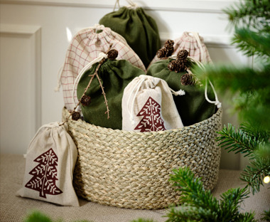 Verschiedene Geschenktaschen mit weihnachtlichem Design in einem Korb liegend