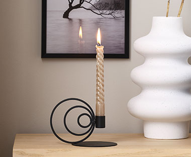 Moderner Kerzenhalter in Schwarz neben einer weißen Vase