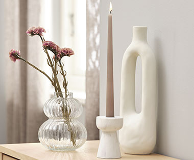 Kerzenständer in Marmor-Optik neben einer Glasvase und einer modernen Vase in Weiß