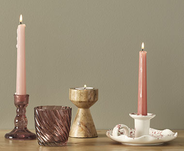 Stabkerzen in Rosa mit verschiedenen Kerzenständer und Teelichthalter auf einer Anrichte