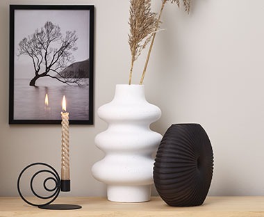 Vasen in Weiß und Schwarz neben einen modernen Kerzenständer