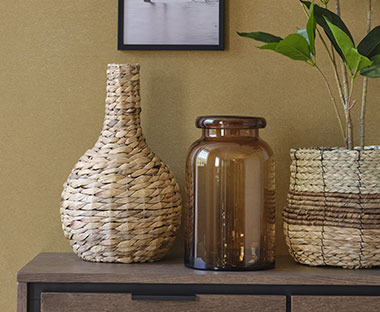 Glasvase in Braun und eine Vase aus Wasserhyazinthe auf einem Konsolentisch