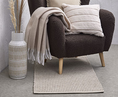Langer und schmaler Teppich in Beige unter einem Sessel