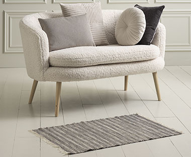 Kleiner Teppich in Grau vor einem Sofa