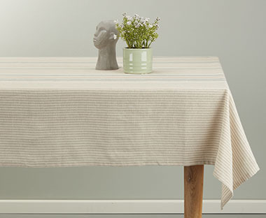 Tischdecke in Beige mit zarten Streifen auf einem Holztisch